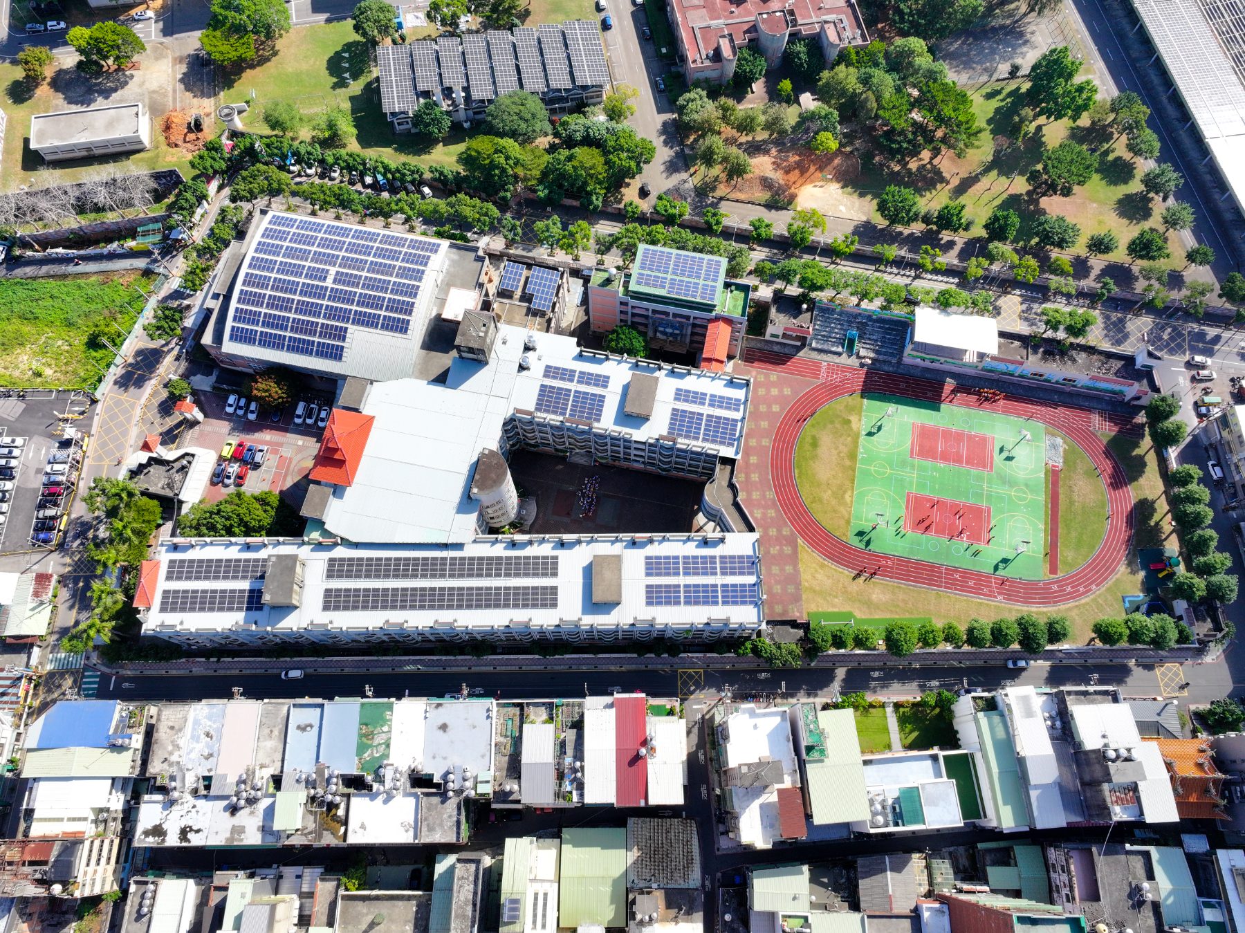 大忠國小俯瞰空拍圖，可見紅色PU跑道、籃球場、教學樓棟與屋頂太陽能板